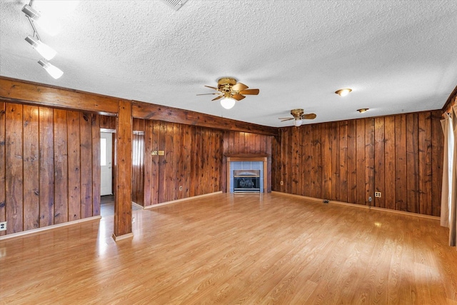 404 S Neal St, Camargo, IL 61919 - unfurnished living room featuring light wood-type flooring, a textured ceiling, a ceiling fan, wooden walls, and a tile fireplace