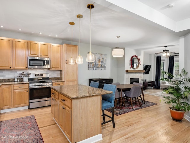 2636 N Fairfield Ave Unit 1N, Chicago, IL 60647 - kitchen with stainless steel appliances, a breakfast bar, backsplash, light wood-style floors, and light brown cabinets