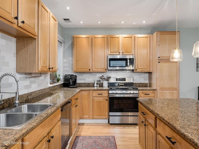 2636 N Fairfield Ave Unit 1N, Chicago, IL 60647 - kitchen with stainless steel appliances, a sink, light wood-type flooring, dark stone countertops, and decorative backsplash