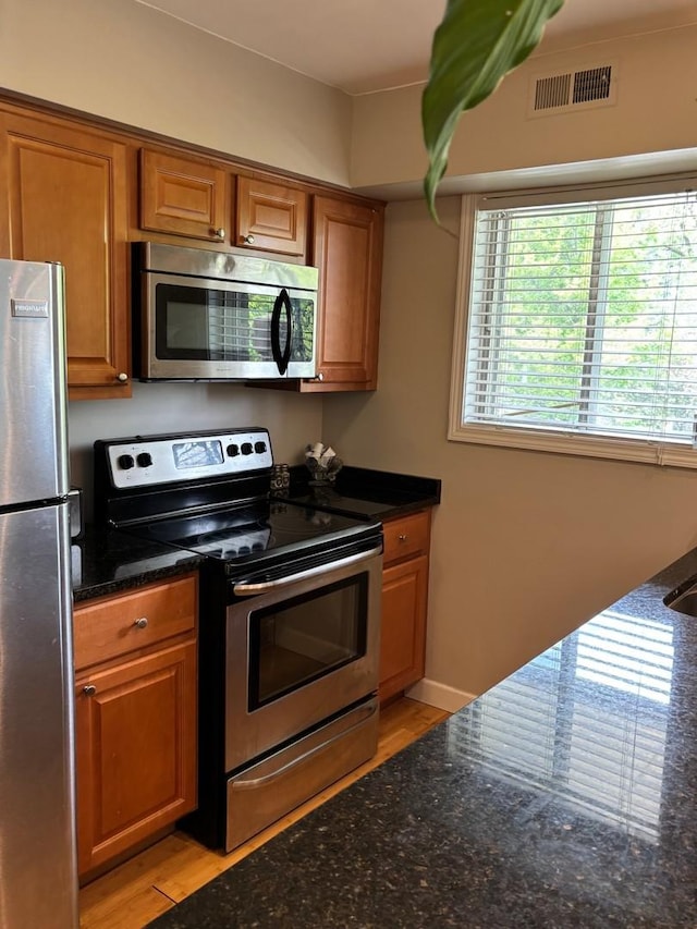 13515 Leclaire Ave Unit 55, Crestwood, IL 60418 - kitchen with stainless steel appliances, brown cabinetry, dark stone countertops, and light wood finished floors