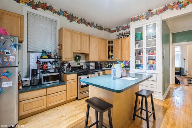 1120 W Newport Ave, Chicago, IL 60657 - kitchen featuring stainless steel appliances, light brown cabinets, light wood finished floors, and a kitchen breakfast bar