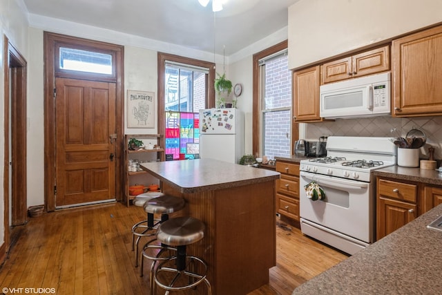 1120 W Newport Ave, Chicago, IL 60657 - kitchen with white appliances, dark countertops, dark wood-type flooring, and a kitchen breakfast bar
