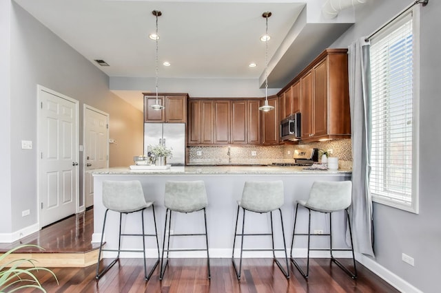 1935 S State St Unit 4, Chicago, IL 60616 - kitchen featuring stainless steel appliances, a peninsula, brown cabinetry, tasteful backsplash, and light stone countertops