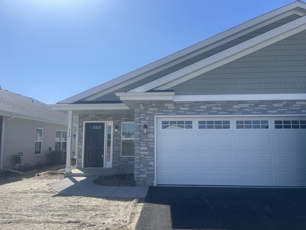552 Fuller Ln, Belvidere, IL 61008 - view of front of home featuring a garage, asphalt driveway, and stone siding