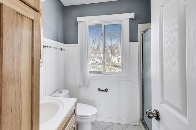 6S009 Steeple Run Dr, Naperville, IL 60540 - bathroom with a shower stall, tile patterned floors, toilet, vanity, and a wainscoted wall