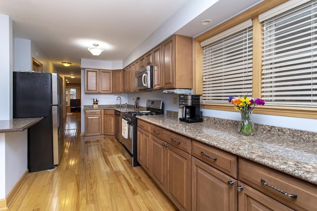 5148 S Newland Ave, Chicago, IL 60638 - kitchen featuring stainless steel appliances, brown cabinets, light wood-style floors, a sink, and light stone countertops