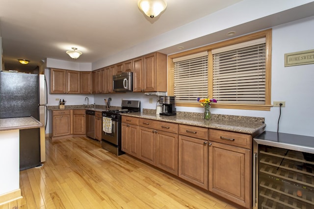 5148 S Newland Ave, Chicago, IL 60638 - kitchen featuring stainless steel appliances, light wood finished floors, a sink, brown cabinets, and wine cooler
