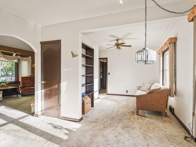 530 Fitch Rd, Rockford, IL 61109 - living area with light colored carpet, a ceiling fan, baseboards, built in shelves, and arched walkways