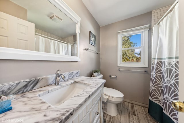 bathroom featuring vanity, toilet, wood finished floors, and baseboards
