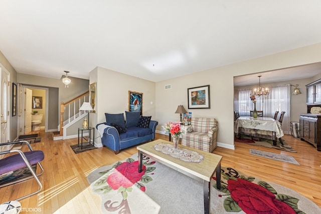 living area with wood finished floors, stairway, a chandelier, and baseboards
