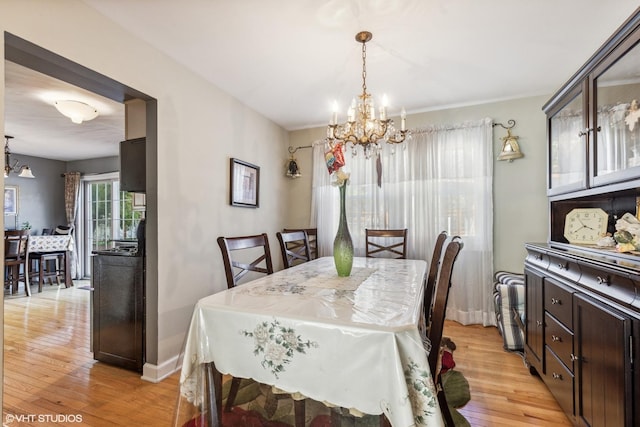 dining area with a chandelier, light wood-style flooring, and baseboards