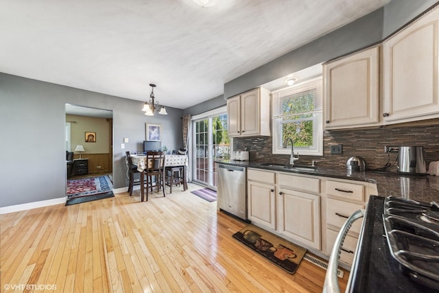 kitchen with stainless steel dishwasher, a sink, black range with gas stovetop, light wood-style flooring, and tasteful backsplash