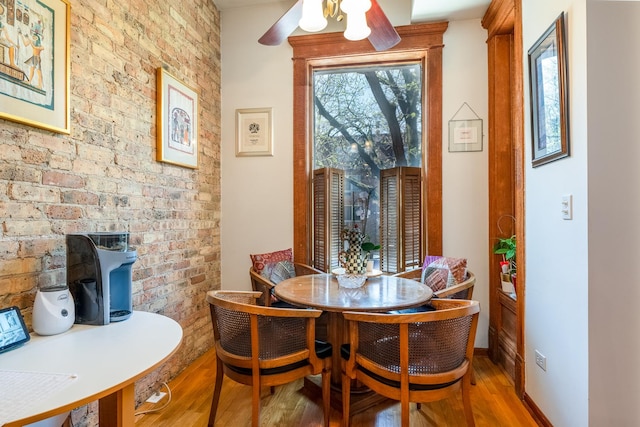 3711 N Pine Grove Ave Unit 2Nw, Chicago, IL 60613 - dining area with wood finished floors, brick wall, a wood stove, ceiling fan, and baseboards