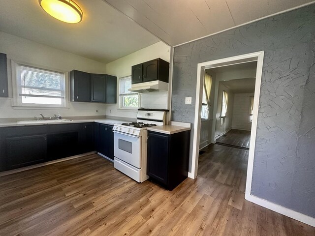 509 E Webster St, Clinton, IL 61727 - kitchen with white gas range, a textured wall, under cabinet range hood, light countertops, and wood finished floors