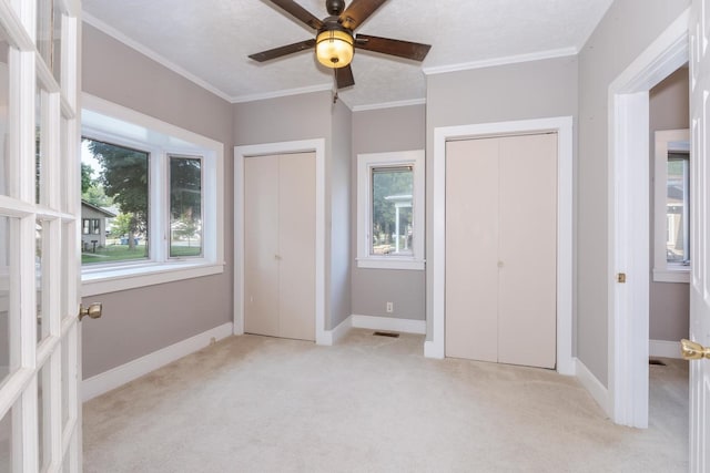 217 W Moulton St, Pontiac, IL 61764 - unfurnished bedroom featuring multiple closets, light colored carpet, multiple windows, crown molding, and ceiling fan