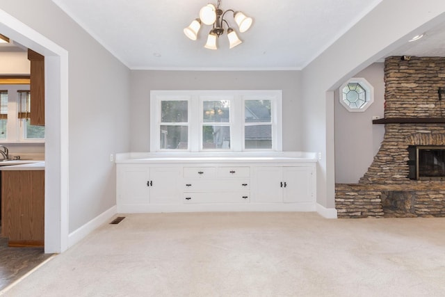 217 W Moulton St, Pontiac, IL 61764 - unfurnished dining area with carpet flooring, a chandelier, a stone fireplace, crown molding, and arched walkways