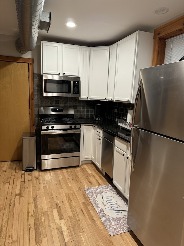 4104 N Mozart St Unit Ge, Chicago, IL 60618 - kitchen featuring appliances with stainless steel finishes, dark countertops, light wood finished floors, white cabinetry, and decorative backsplash