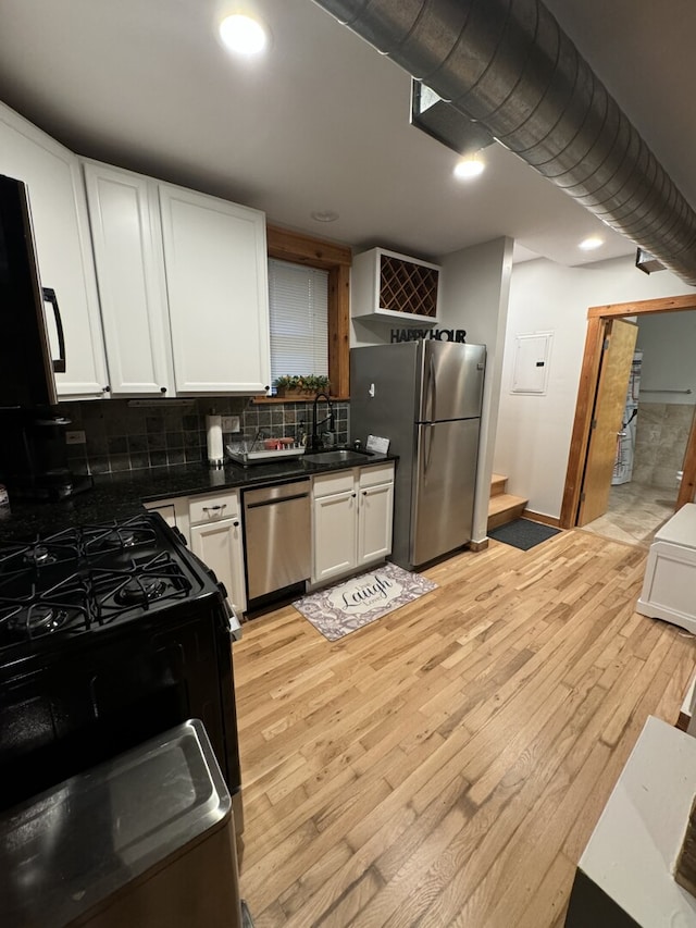 4104 N Mozart St Unit Ge, Chicago, IL 60618 - kitchen featuring stainless steel appliances, a sink, light wood finished floors, dark countertops, and white cabinetry