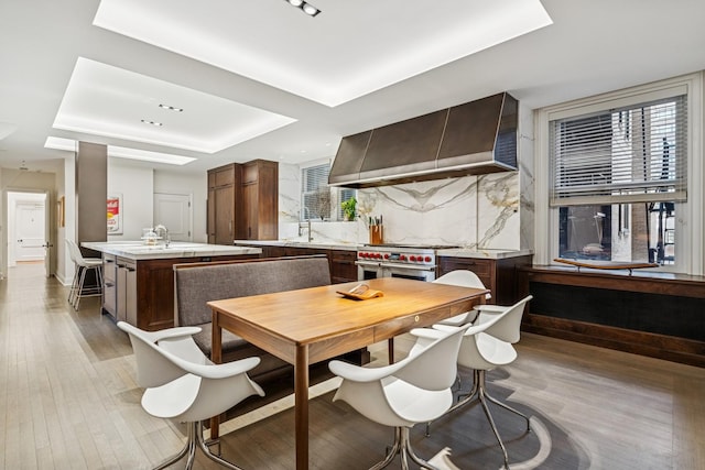 209 E Lake Shore Dr Unit 3W, Chicago, IL 60611 - kitchen with wall chimney range hood, a raised ceiling, double oven range, an island with sink, and light countertops