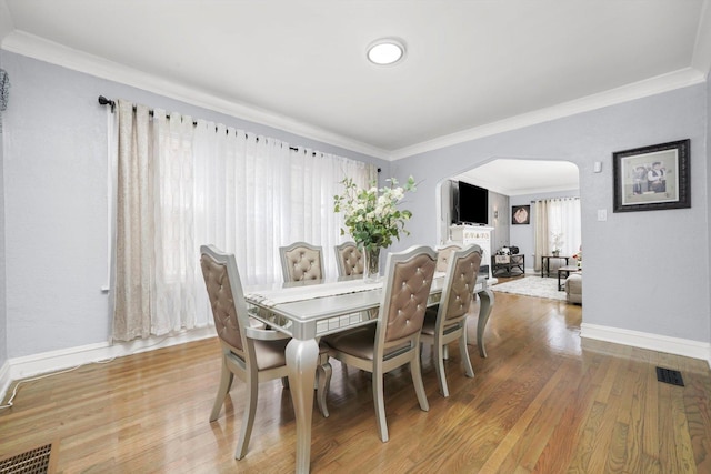 10807 S Wentworth Ave, Chicago, IL 60628 - dining room featuring arched walkways, baseboards, crown molding, and wood finished floors