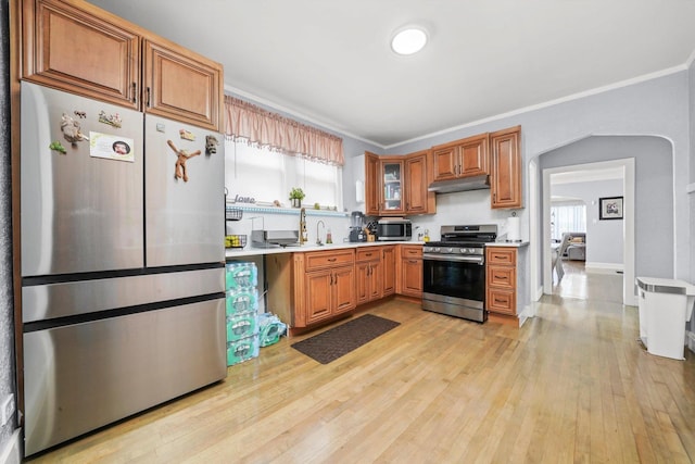 10807 S Wentworth Ave, Chicago, IL 60628 - kitchen featuring appliances with stainless steel finishes, light countertops, light wood finished floors, under cabinet range hood, and brown cabinetry