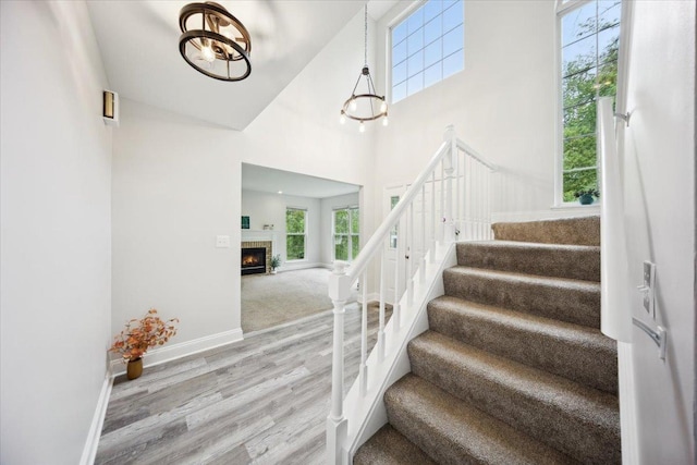 1148 Coldspring Rd Unit 0, Elgin, IL 60120 - staircase featuring wood finished floors, baseboards, a towering ceiling, a tile fireplace, and a chandelier