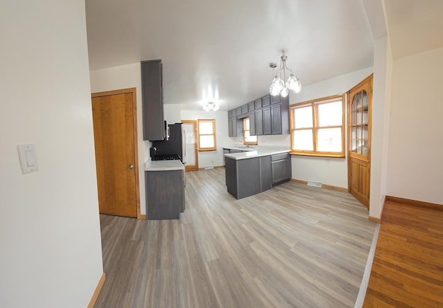 18433 Arcadia St, Lansing, IL 60438 - kitchen with light wood finished floors, light countertops, a chandelier, and a peninsula