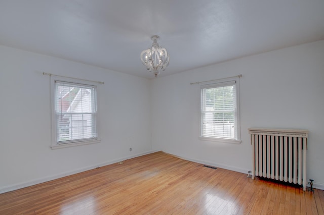 110 N Newton St, Goodland, IN 47948 - unfurnished room with radiator heating unit, a chandelier, light wood-style floors, and baseboards