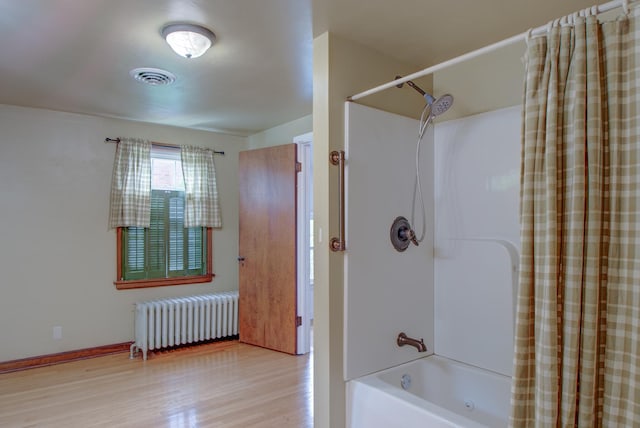 110 N Newton St, Goodland, IN 47948 - full bath with radiator heating unit, shower / tub combo with curtain, and wood finished floors