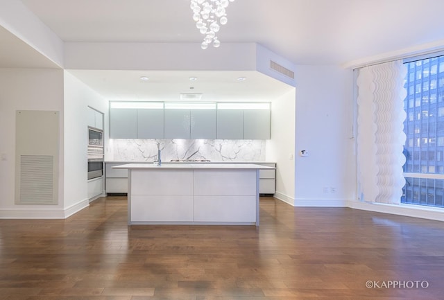 401 N Wabash Ave Unit 39G, Chicago, IL 60611 - kitchen featuring modern cabinets, a center island with sink, stainless steel microwave, dark wood-type flooring, and backsplash