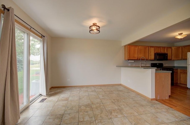 1716 Waters Edge Dr Unit 1716, Minooka, IL 60447 - kitchen with black microwave, a peninsula, freestanding refrigerator, a sink, and baseboards