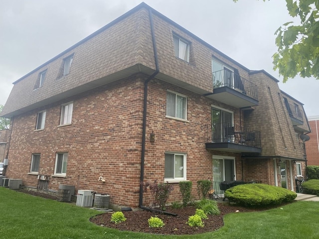 10715 S Keating Ave Unit 1C, Oak Lawn, IL 60453 - view of home's exterior with a balcony, mansard roof, brick siding, a lawn, and cooling unit