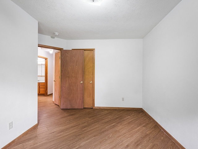 119 SE Brandywine Dr, Poplar Grove, IL 61065 - empty room with light wood-type flooring, baseboards, a textured ceiling, and a smoke detector