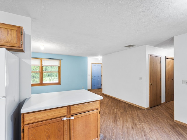 119 SE Brandywine Dr, Poplar Grove, IL 61065 - kitchen featuring wood finished floors, freestanding refrigerator, a textured ceiling, light countertops, and baseboards
