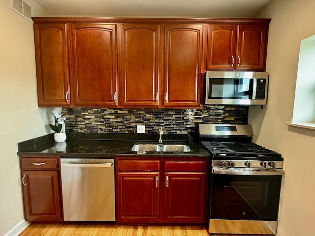 6324 S Kimbark Ave Unit 404, Chicago, IL 60637 - kitchen with stainless steel appliances, a sink, dark stone countertops, backsplash, and light wood finished floors