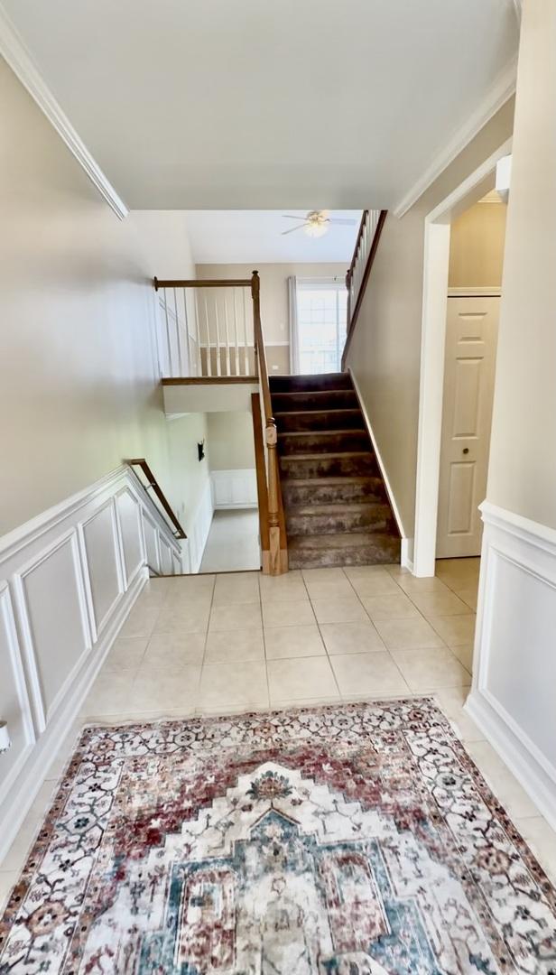 1708 S Fieldstone Dr, Shorewood, IL 60404 - stairway featuring a ceiling fan, tile patterned floors, a wainscoted wall, and a decorative wall
