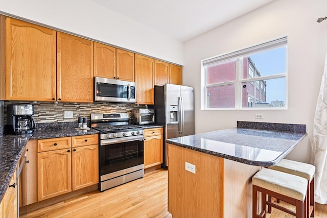7511 Brown Ave Unit N, Forest Park, IL 60130 - kitchen with appliances with stainless steel finishes, light wood-type flooring, a peninsula, decorative backsplash, and dark stone counters