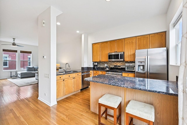 7511 Brown Ave Unit N, Forest Park, IL 60130 - kitchen with appliances with stainless steel finishes, a peninsula, light wood-style flooring, decorative backsplash, and a ceiling fan