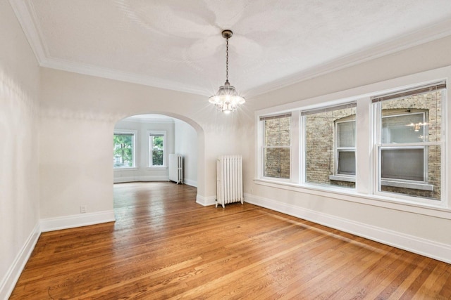 217 S Oak Park Ave, Oak Park, IL 60302 - empty room featuring radiator, arched walkways, a chandelier, crown molding, and light wood finished floors
