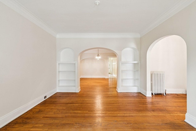 217 S Oak Park Ave, Oak Park, IL 60302 - empty room with built in features, radiator, arched walkways, crown molding, and wood finished floors