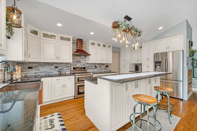 26138 Oak Ridge Ct, Channahon, IL 60410 - kitchen featuring appliances with stainless steel finishes, wall chimney range hood, light wood finished floors, a kitchen breakfast bar, and lofted ceiling