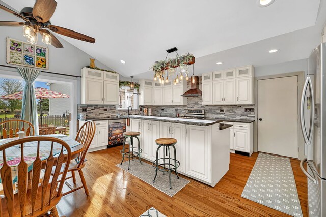 26138 Oak Ridge Ct, Channahon, IL 60410 - kitchen featuring freestanding refrigerator, wall chimney range hood, ceiling fan, range, and vaulted ceiling