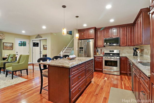 4125 Victoria Dr, Hoffman Estates, IL 60192 - kitchen featuring stainless steel appliances, a breakfast bar area, light wood-type flooring, hanging light fixtures, and backsplash
