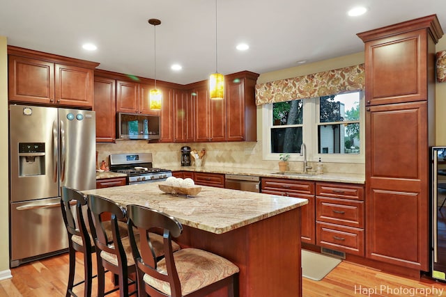 4125 Victoria Dr, Hoffman Estates, IL 60192 - kitchen with stainless steel appliances, a sink, light wood-style flooring, light stone counters, and a center island