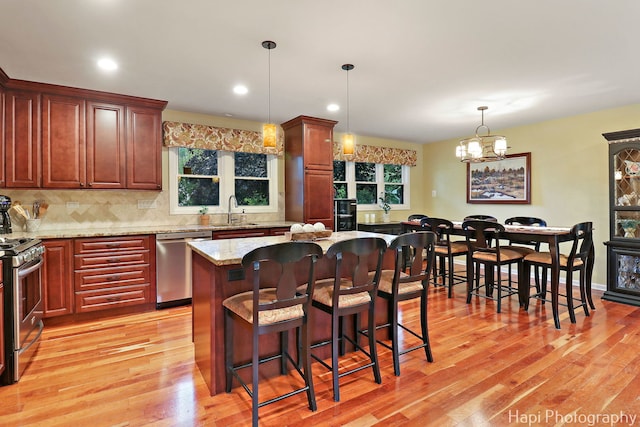 4125 Victoria Dr, Hoffman Estates, IL 60192 - kitchen with appliances with stainless steel finishes, light wood-type flooring, decorative backsplash, a sink, and a breakfast bar