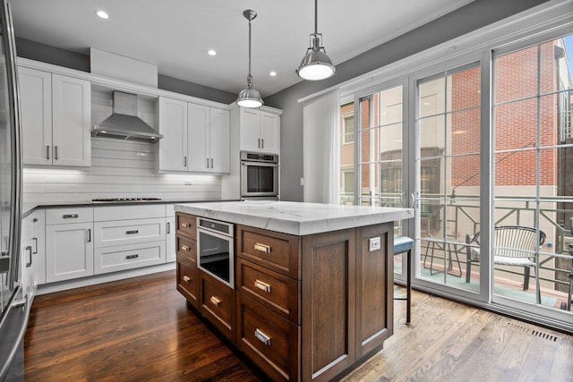 1429 S Prairie Ave, Chicago, IL 60605 - kitchen featuring wall chimney exhaust hood, oven, gas cooktop, dark wood-style flooring, and white cabinetry