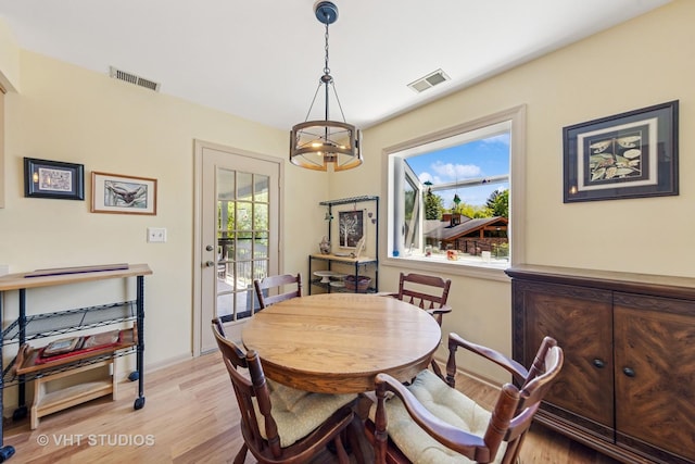 dining room featuring light wood-type flooring, a chandelier, and baseboards