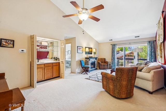 living area featuring light colored carpet, high vaulted ceiling, ceiling fan, a fireplace, and baseboards