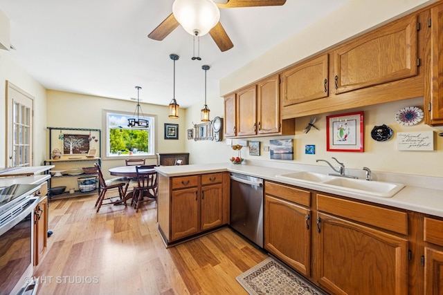 kitchen with appliances with stainless steel finishes, a sink, brown cabinetry, a peninsula, and light wood-style flooring