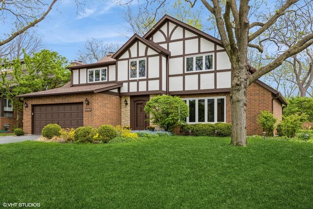 6483 Indianhead Trl, Indian Head Park, IL 60525 - tudor house with stucco siding, a chimney, a front yard, brick siding, and driveway